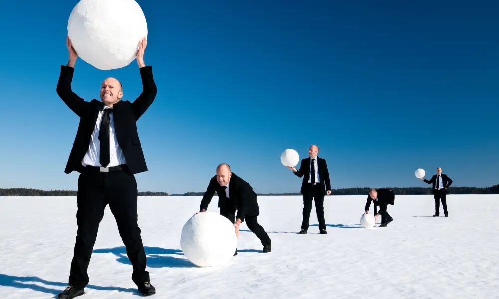 Ilustração do efeito bola de neve crescendo e eliminando dívidas pequenas.