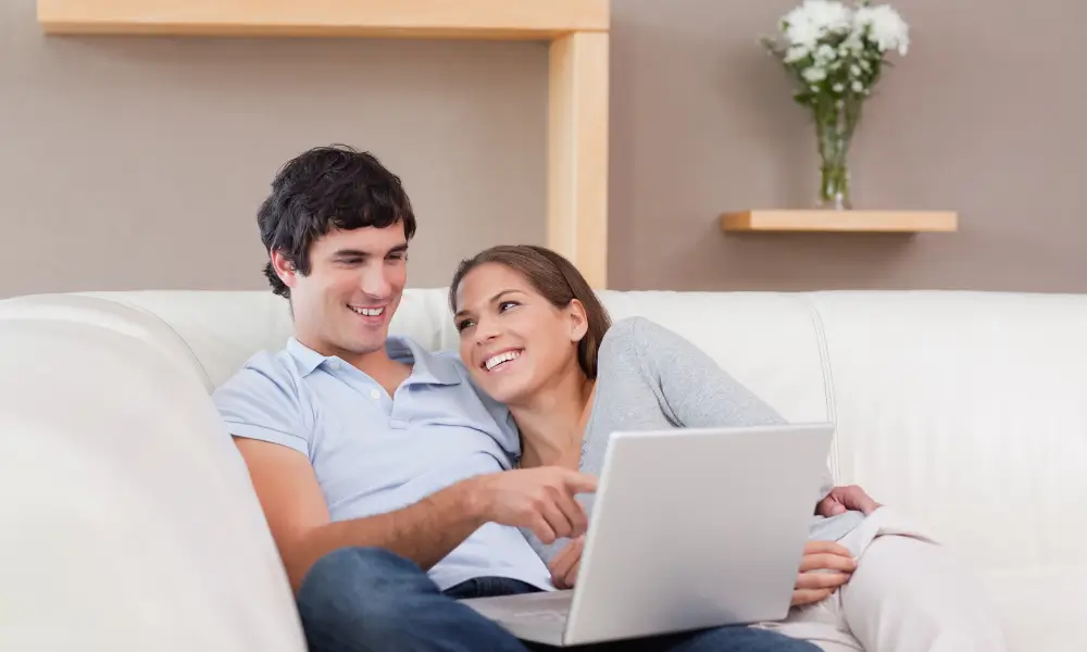 Casal planejando finanças e calculando divisão de despesas no computador.